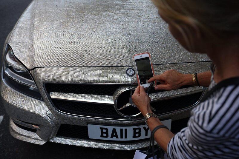 A woman photographs a Mercedes S-class which has been covered in Swarovski crystals in Knightsbridge. Carl Court / Getty Images