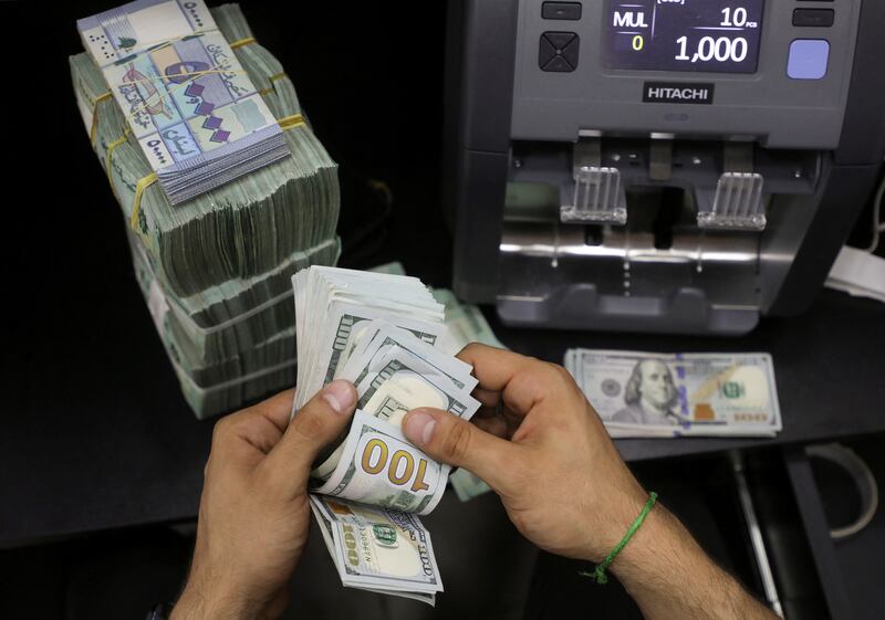 A money vendor counts US banknotes next to Lebanese pounds at a currency exchange in Beirut. Inflation in the country surged to 206 per cent last month. Reuters