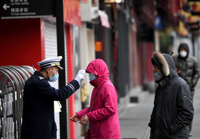 A security guard checks the temperature of people entering Yu Park in Shanghai. AFP