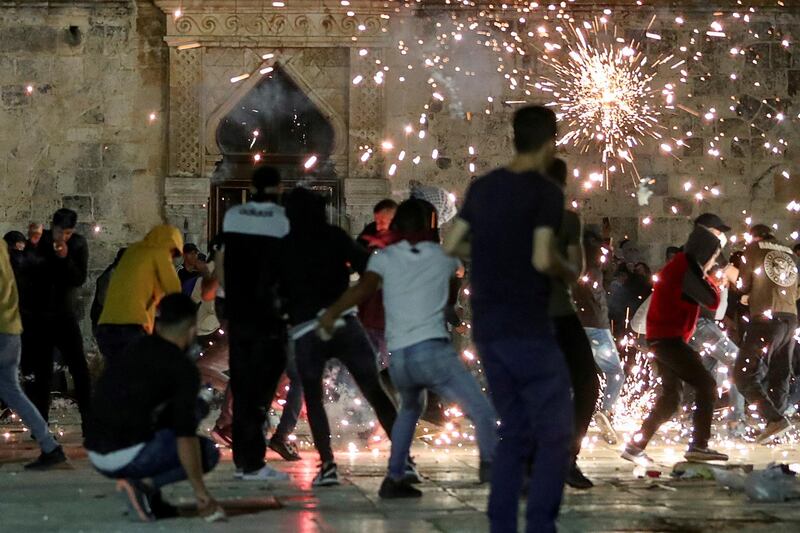 Palestinians demonstrators react as Israeli police fire stun grenades. Reuters