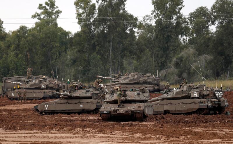 Israelis stand near their Merkava tanks at a gathering point next to the Israeli border with Gaza on March 29, 2019.   EPA