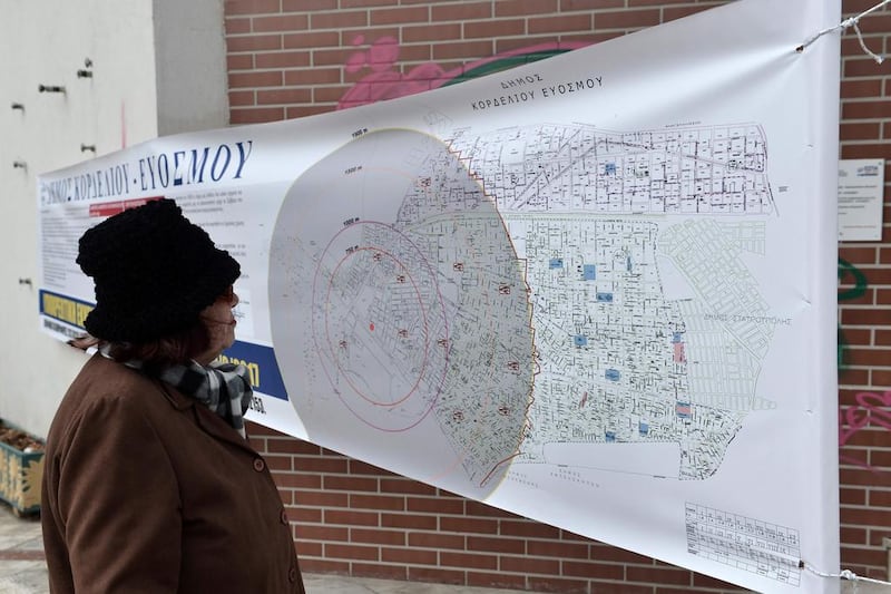 A resident looks at a map showing the radius of the evacuation area, ahead of an operation to defuse a World War II bomb in Kordelio, a suburb of Thessaloniki, on February 12, 2017 where Greek authorities evacuated some 70,000 people. Sakis Mitroldis/AFP