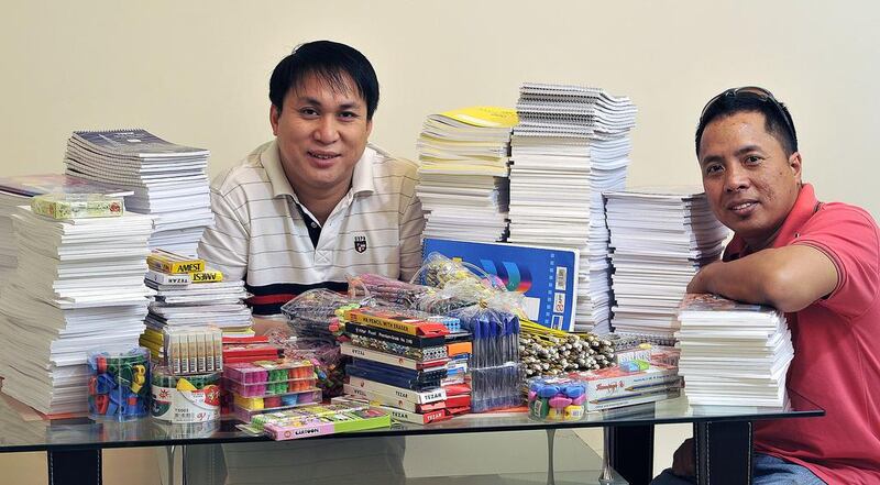 Wilfredo Aguilar and Ryan Cabug sit with school supplies to be donated to underprivileged schoolchildren in the Philippines as part of an education project called “lapis at papel” (pencil and paper). Charles Crowell for The National 