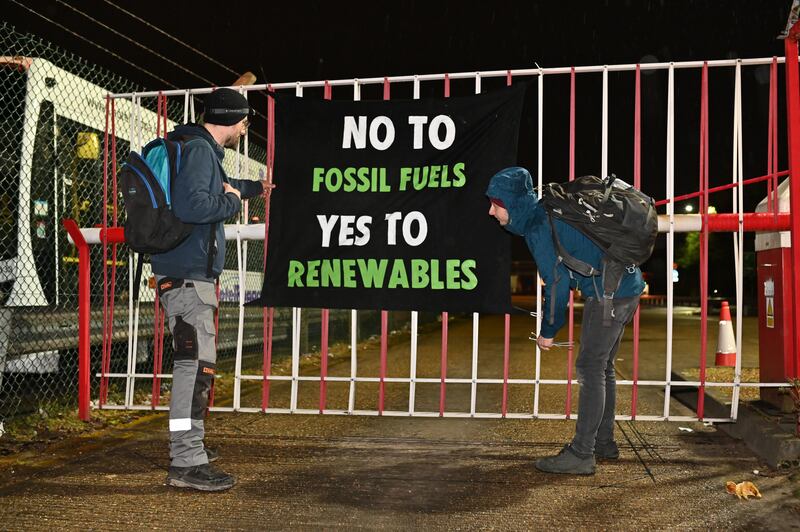Extinction Rebellion protesters hang a banner on the gates of an Esso oil facility near Heathrow Airport in London on Monday. Photo: Extinction Rebellion