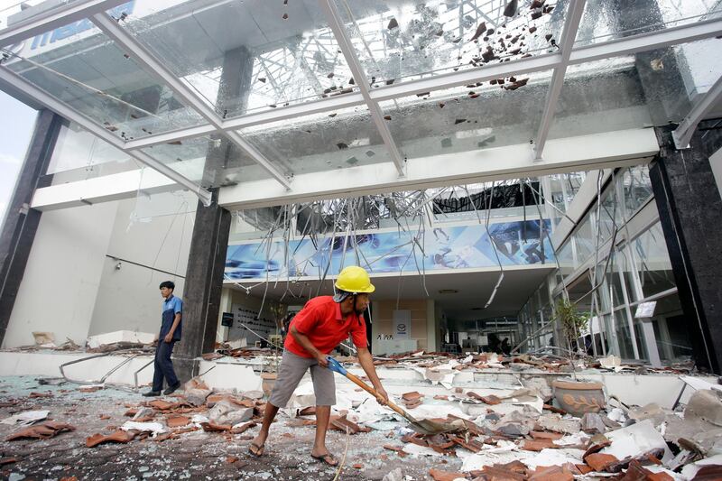 Workers clean up the debris at a building damaged by an earthquake in Bali, Indonesia. AP Photo