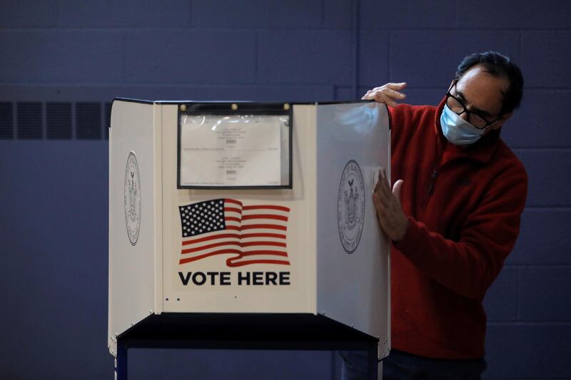 A man sanitizes a privacy booth to fight the spread of coronavirus disease at a polling station opened for early voting at Our Lady Help of Christians in Staten Island, New York City, U.S. REUTERS