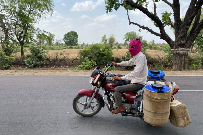 A milkman with containers covered with wet jute sacks to protect the milk from the severe heat in Lalitpur, Uttar Pradesh state