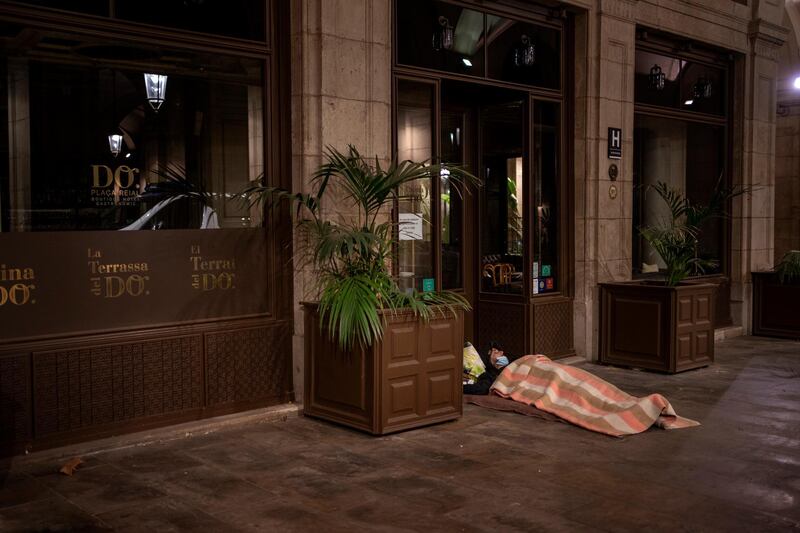 A homeless person sleeps at the entrance of a restaurant closed due to the resurgence of the coronavirus. AP