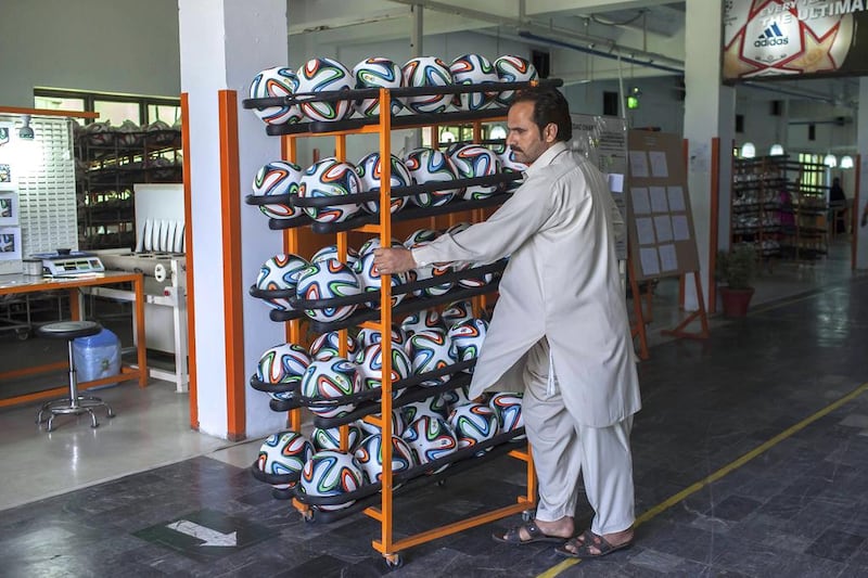 An employee takes finished balls out of the production area inside the football factory that produces official match balls for the 2014 World Cup in Brazil, in Sialkot, Punjab province. Sara Farid / Reuters

