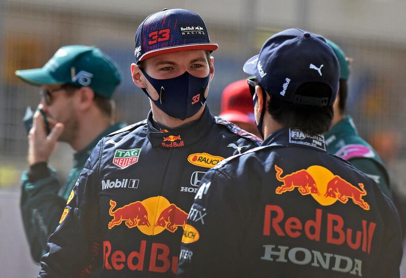 Red Bull's Dutch driver Max Verstappen (C) and Red Bull's Mexican driver Sergio Perez (C-R) chat ahead of the first day pre-season testing at the Bahrain International Circuit in the city of Sakhir. AFP