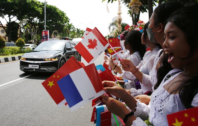 Students wave flags of G20 member nations to greet world leaders, on a street near Ngurah Rai International airport in Bali. EPA