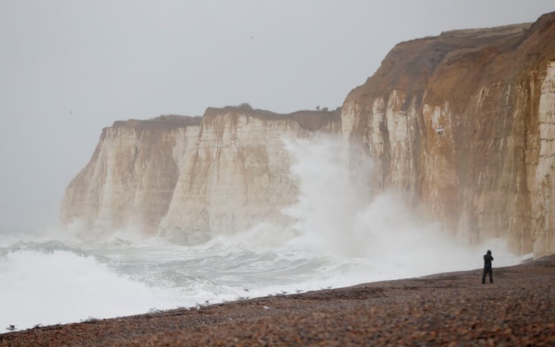 A man takes photographs as waves hit the cliffs in Newhaven.  Reuters