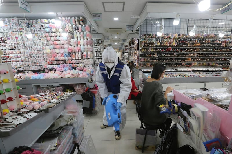 A worker wearing protective gears sprays disinfectant inside a shop in Seoul. AP Photo