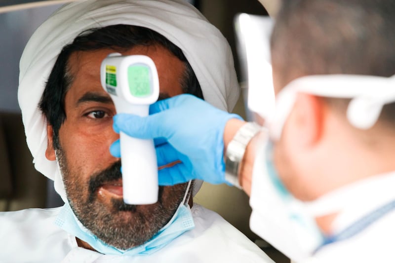 A health worker checks a man's temperature before conducting a coronavirus test at a drive-through testing centre.