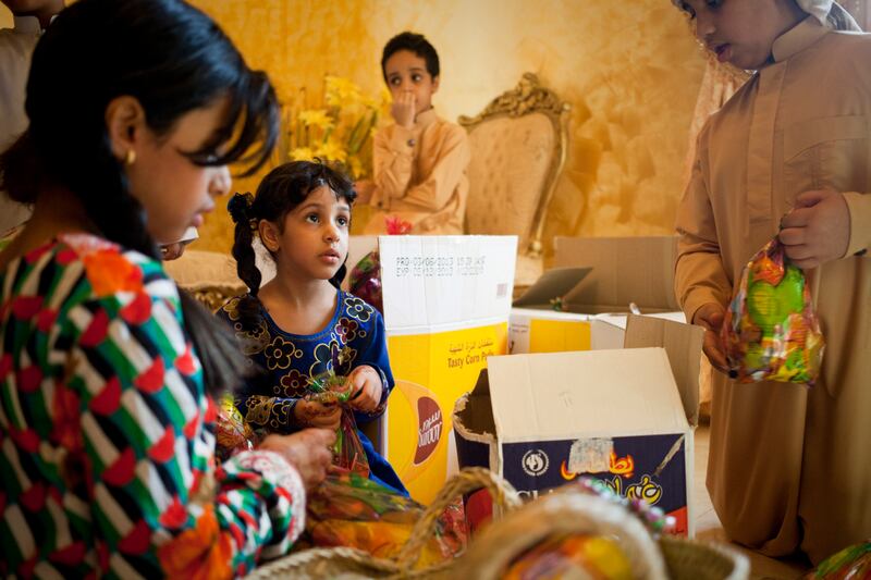 Sharjah, United Arab Emirates - June 23 2013 - Maitha Al Jabri, 4, (center) packs little bags filled with sweets and crisps with her cousins at their home in the Leyyah district of the city. They are preparing for Hag El Leila, an Emirati tradition that occurs every year 15 days before the start of the month of Ramadan. The tradition involves children walking from door-to-door singing and collecting sweets and money. (Razan Alzayani / The National)  FOR RYM GHAZAL STORY  *** Local Caption ***  RA0623_hag_el_layla_001.jpg