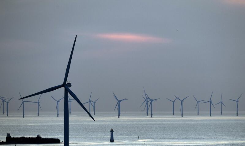 (FILES) In this file photo taken on May 14, 2019 New Brighton lighthouse is pictured at sunset, in New Brighton, at the mouth of the river Mersey, in north-west England on May 14, 2019, with the Burbo Bank Offshore Wind Farm visible on the horizon. Britain, a global leader in offshore wind energy, plans to make the sector one of the pillars of its transition to carbon neutrality in the coming decades. The country aims to quadruple its offshore electricity production capacity by 2030 by utilising the windswept North Sea and a favourable policy environment. / AFP / Paul ELLIS
