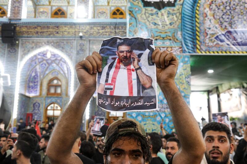 A mourner holds up a poster showing assassinated Iraqi anti-government activist Ihab al-Wazni (Ehab al-Ouazni) during his funeral at the Imam Hussein Shrine in the central holy shrine city of Karbala on May 9, 2021. Wazni, a coordinator of protests in the Shiite shrine city of Karbala, was a vocal opponent of corruption, the stranglehold of Tehran-linked armed groups and Iran's influence in Iraq. He was shot overnight outside his home by men on motorbikes, in an ambush caught on surveillance cameras. He had narrowly escaped death in December 2019, when men on motorbikes used silenced weapons to kill fellow activist Fahem al-Tai as he was dropping him home in Karbala, where pro-Tehran armed groups are legion. / AFP / Mohammed SAWAF
