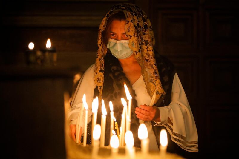 A woman lights candles during an Orthodox Easter religious service at the Armenian cathedral in Bucharest, Romania, on Saturday, May 1, 2021. AP Photo
