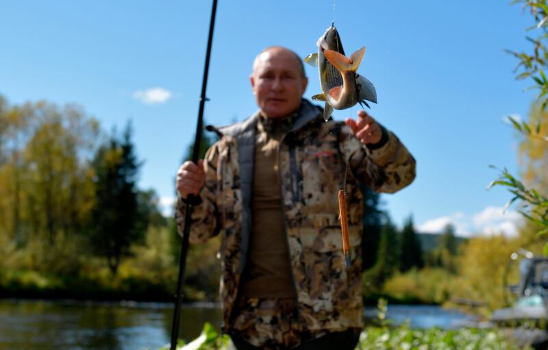 In this undated pool photo released by the Kremlin Press Service via Sputnik on Sunday, Sept.  26, 2021, Russian President Vladimir Putin catches his trophy as he fishes during his and Russian Defense Minister Sergei Shoigu short vacation in early September, 2021 after his working visit to the Primorye and the Amur Region of the Russian Far East.  (Alexei Druzhinin, Sputnik, Kremlin Pool Photo via AP)