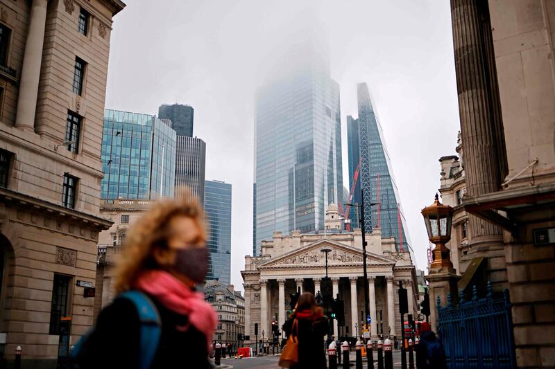 A pedestrian wearing a protective face covering crosses the road near the Royal Exchange and the Bank of England in the City of London. AFP