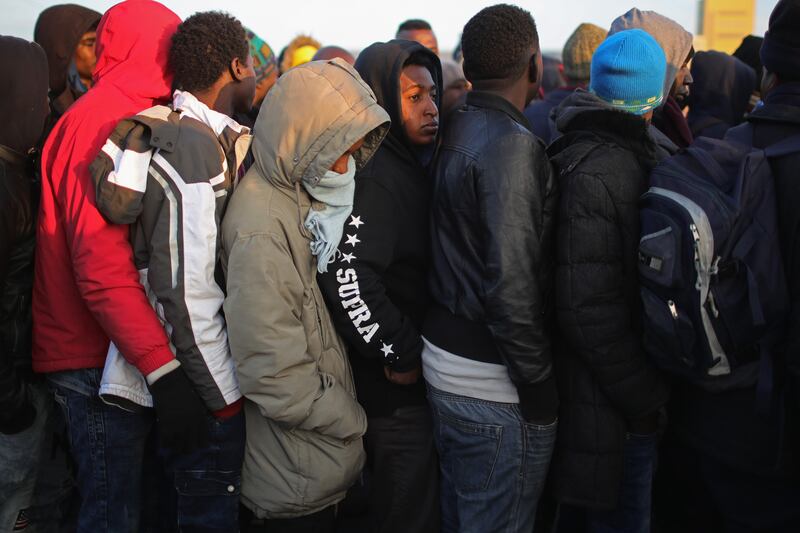 Sudanese migrants queue in the cold weather for buses to leave the camp