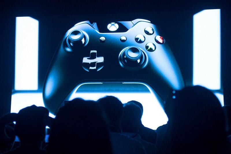 People look at a screen showing a controller during the presentation of the Xbox One in Shanghai on July 30. The Xbox One will launch in China in September, the first games console to be officially released on the mainland after Beijing lifted a ban on the devices, which it had imposed in 2000. Johannes Eisele / AFP
