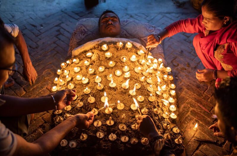 A Nepalese Hindu lies covered with oil lamps as an offering to the Hindu goddess Durga during the Dashain festival celebration at the Baramahini Temple in Bhaktapur, Nepal.   EPA