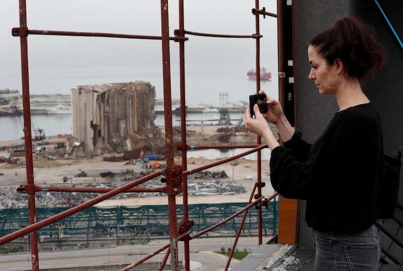Joana Dagher, 33, who lost her memory for two full months from the trauma she suffered in the massive August explosion at the Beirut port takes pictures of the explosion scene from her damaged apartment rooftop. AP