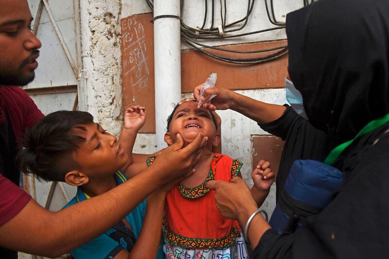 TOPSHOT - A health worker administers polio vaccine drops to a child during a polio vaccination door-to-door campaign in the Pakistan's port city of Karachi on July 20, 2020. Pakistan on July 20 resumed its polio vaccination campaign after a four-month pause due to the coronavirus outbreak, with health authorities predicting a surge in cases of the crippling disease.     
 / AFP / Rizwan TABASSUM
