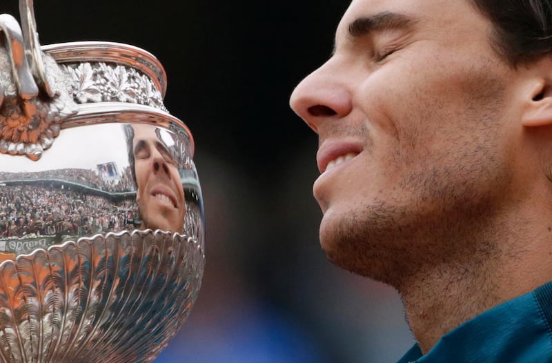 Spain's Rafael Nadal celebrates with the trophy following his victory over Spain's David Ferrer at the end of their French tennis Open final match at the Roland Garros stadium in Paris on June 9, 2013. AFP PHOTO / KENZO TRIBOUILLARD (Photo by KENZO TRIBOUILLARD / AFP)
