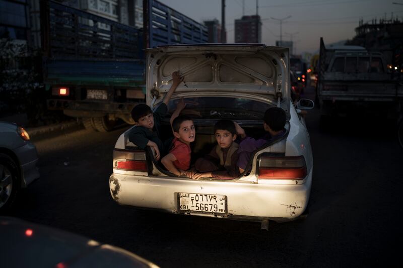 Afghan boys ride in the boot of a car. Photo: AP