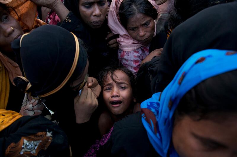 FILE - In this Sept. 20, 2017, file photo, Rohingya Muslim child cries as she stands amid a crowd of elders to receive food being distributed near Balukhali refugee camp in Cox's Bazar, Bangladesh. Myanmar, a predominantly Buddhist nation of 60 million, was basking in international praise just a few years ago as it transitioned to democracy after a half-century of dictatorship. Since then, a campaign of killings, rape and arson attacks by security forces and Buddhist-aligned mobs have sent more than 850,000 of the country's 1.3 million Rohingya fleeing. (AP Photo/Bernat Armangue, File)