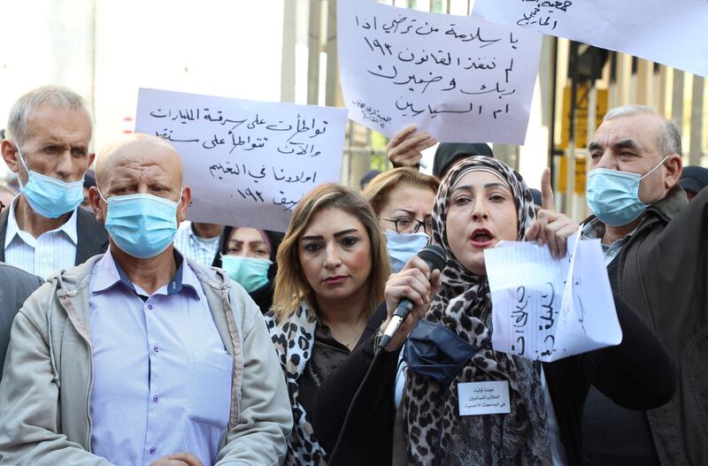 People hold placards during a protest by parents of students studying abroad in front of Lebanon's Central bank in Beirut, Lebanon November 18, 2020. Picture taken November 18, 2020. REUTERS/Mohamed Azakir