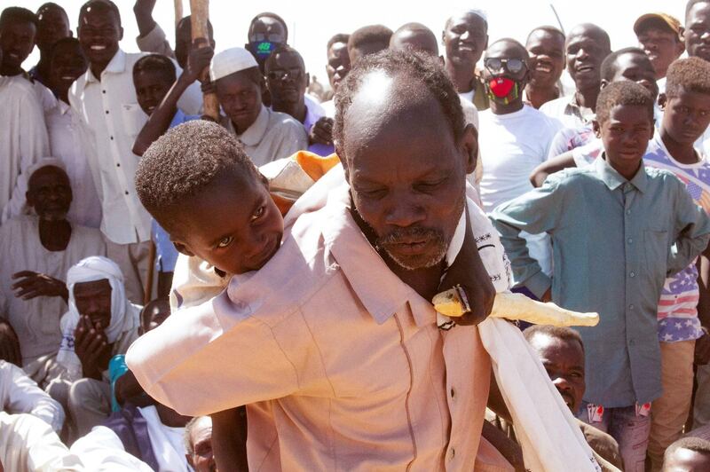 A Sudanese man carries a child as he takes part in a sit in to protest against the end of the mandate of the United Nations and African Union peacekeeping mission (UNAMID), in Kalma camp for internally displaced people in Nyala, the capital of South Darfur, on December 30, 2020.  The United Nations Security Council has agreed to end the UNAMID's long-running peacekeeping mission in Darfur when its mandate ceases on December 31.
The withdrawal of UNAMID, deployed since 2007 and which had 16,000 peacekeepers at its peak, will begin January 1 and is expected to be completed by June 30 2021.
 / AFP / -
