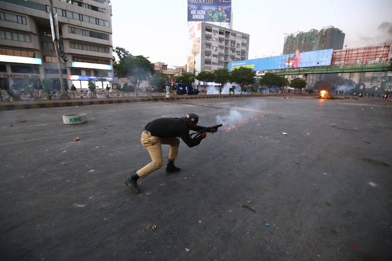 An officer fires a tear gas shell at Mr Khan's supporters in Karachi. EPA