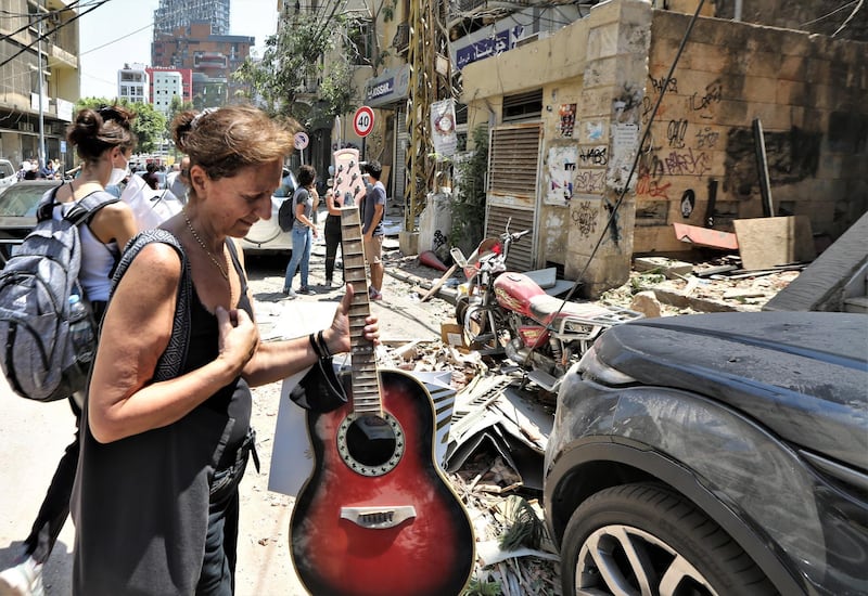 People carry belongings after evacuating their damaged housing units at area of Mar Mikhael and Gemayzeh.  EPA