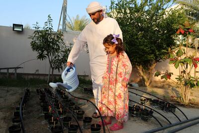 Abdulaziz Bin Redha with daughter Zahra, 5, watering the pots in his back garden. Chris Whiteoak / The National