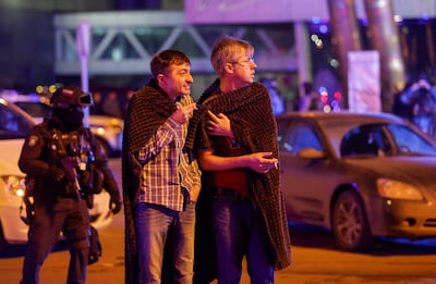 Men stand near the venue following the shooting. Reuters