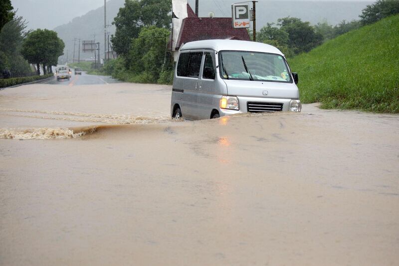 A minivan drives through a flooded street in Yatsushiro, Kumamoto prefecture. EPA