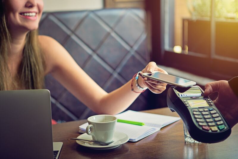 Young woman is paying in the cafe using her mobile phone. Getty Images