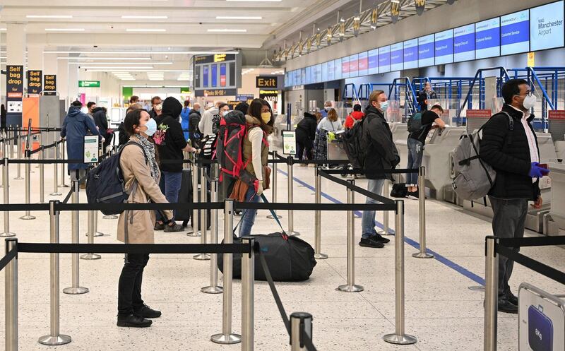 Passengers socially distance as they queue at a check-in desk at Manchester Airport. AFP