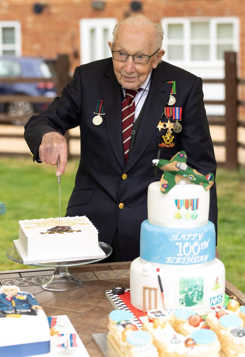 Captain Tom Moore poses for a photograph with cakes to celebrate his 100th birthday. AFP