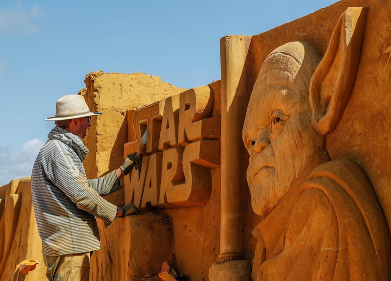 A sand carver works on a Yoda sculpture. Yves Herman / Reuters