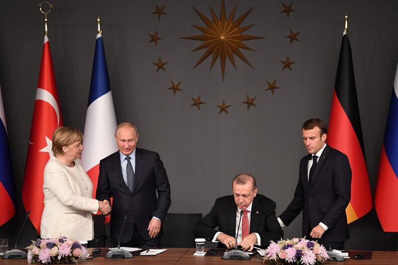 TOPSHOT - Russian President Vladimir Putin (2ndL) and German Chancellor Angela Merkel (L) shake hands after a conference with Turkish President Recep Tayyip Erdogan (2ndR) and French President Emmanuel Macron (R) during a summit called to attempt to find a lasting political solution to the civil war in Syria which has claimed in excess of 350 000 lives, at Vahdettin Mansion in Istanbul, on October 27, 2018. The leaders of Turkey, Russia, France and Germany are set to meet in Istanbul to try to find a lasting political solution to the Syrian civil war and salvage a fragile ceasefire in a rebel-held northern province. / AFP / OZAN KOSE
