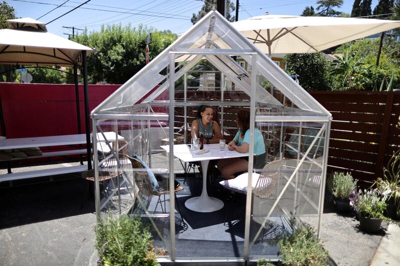 Nuria Bosch, 29, and Dria Abramson, 29, eat lunch in a social-distancing greenhouse dining pod, in the former car parking of the Lady Byrd Cafe in Los Angeles, California. Reuters