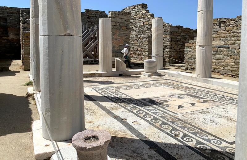 An Archaeological Service worker walks past marble columns on the island of Delos, an ancient center of religious and commercial life, in Greece.