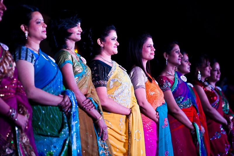 1st runner-up Nisha Sharma (center, yellow), 37, stands in the line of 12 semifinalists as they are introduced to the audience at the inaugural AAS Housewives Awards 2012 on 19th May 2012 in New Delhi, India. Out of 12 selected semi-finalists, 6 finalists will be chosen based on a question and answer session on stage, and other criteria such as poise. The winner, and 1st and 2nd runner-ups are Jyoti Nagpal (#2), Nisha Sharma (#7) and Seema Sharma (#4)respectively. The awards also served as a platform for Cervical Cancer Awareness. Photo by Suzanne Lee for The National