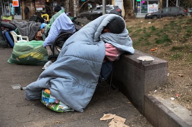 A man sleeps on a park bench wrapped in a blanket outside a subway station in the Queens borough of New York City, U. S. , March 31, 2022.   REUTERS / Shannon Stapleton