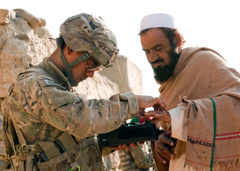 In this Nov. 5, 2012, photo provided by the U.S. Army, U.S. Army Pfc. Mark Domingo, left, takes an Afghan man's fingerprints in the village of Dande Fariqan, in Afghanistan's Khowst Province, as part of the military's effort to gather biometric data on the residents. Domingo, an Army veteran who converted to Islam and discussed launching various terror attacks throughout Southern California, was arrested as he plotted to bomb a white supremacist rally as retribution for the New Zealand mosque attacks, federal prosecutors said Monday, April 29, 2019. (Sgt. Christopher Bonebrake/U.S. Army via AP)