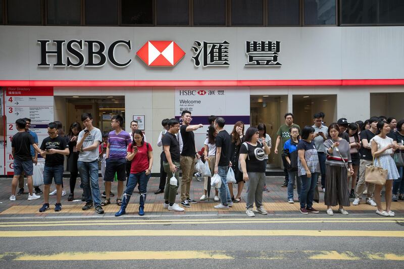 Pedestrians wait to cross a road in front of an HSBC Holdings Plc bank branch in Hong Kong, China, on Thursday, July 25, 2019. HSBC is scheduled to release interim earnings results on Aug. 5. Photographer: Paul Yeung/Bloomberg